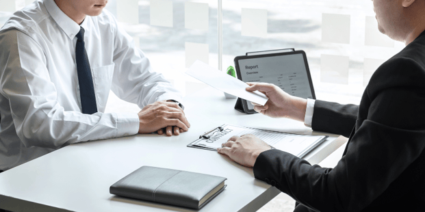Two men talk over a office desk